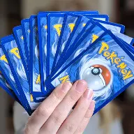 Une main tenant des cartes du jeu de cartes à collectionner Pokémon, prête à se battre.