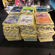 Three huge stacks of bulk Pokémon cards ready to be sold