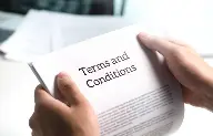 Deux mains tenant un papier blanc sur lequel on peut lire "terms and conditions".