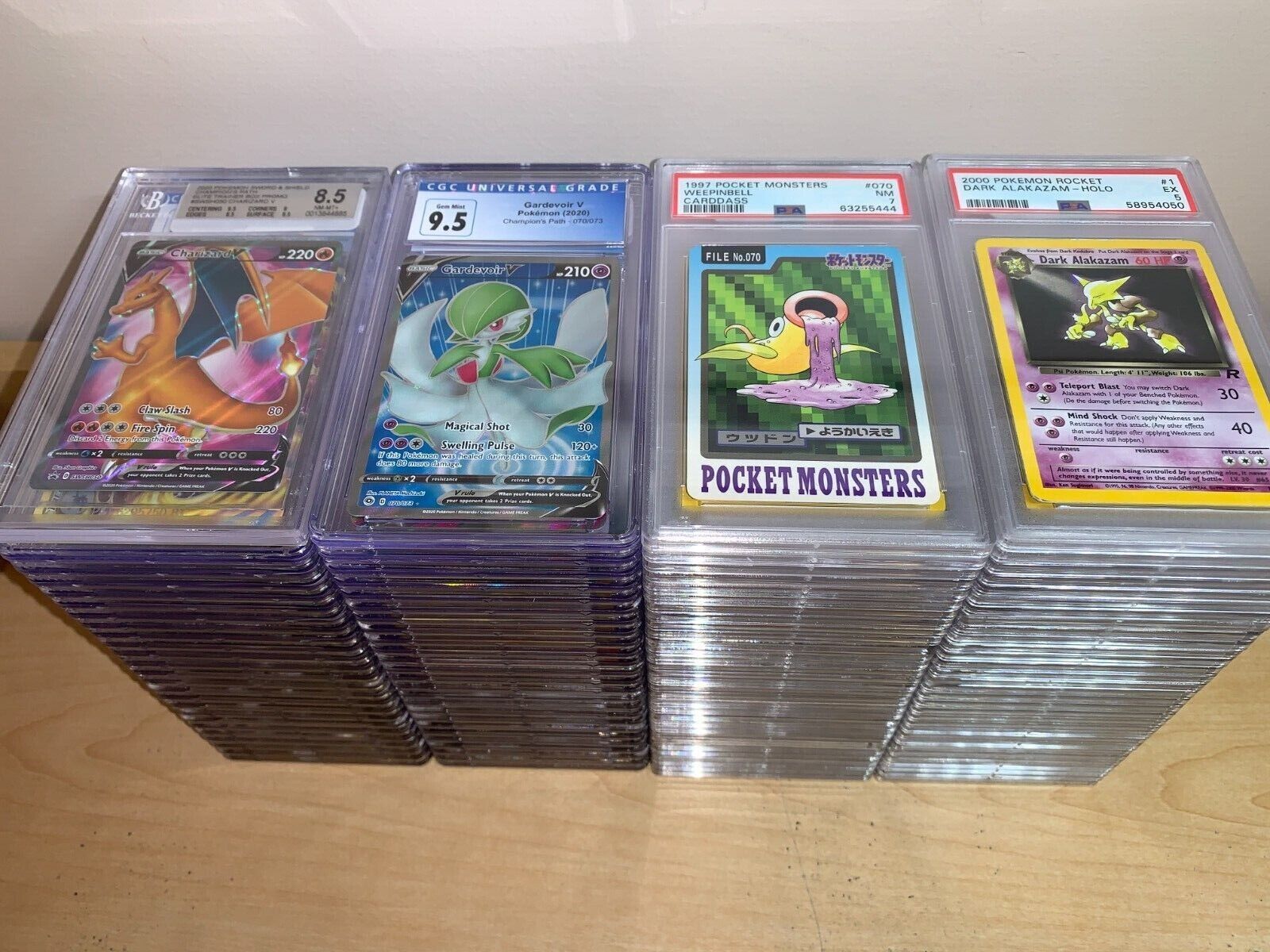 Grade your Cards Four stacks of graded Pokémon cards featuring Charizard, Weepingbell, Alakazam and Gardevoir